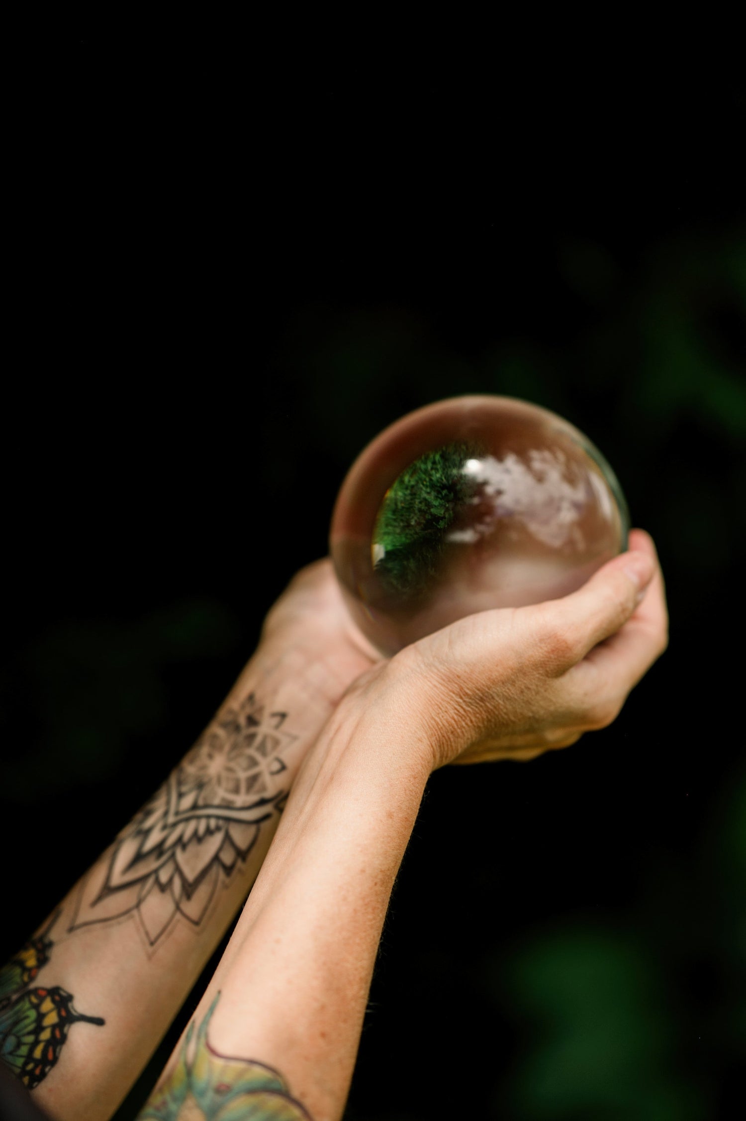two hands hold a clear quartz sphere