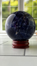 Load image into Gallery viewer, Stunning 2 inch Sodalite Sphere with deep royal blue color with a white calcite pattern, wooden stand included.
